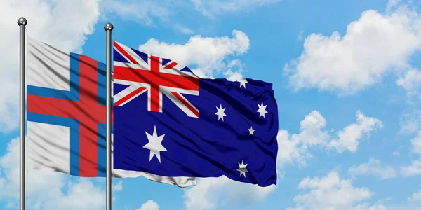 Bandera de las Islas Feroe y Australia ondeando en el viento contra el cielo azul nublado blanco juntos. Concepto diplomático, relaciones internacionales . — Foto de Stock