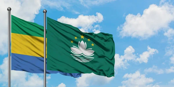 Gabon and Macao flag waving in the wind against white cloudy blue sky together. Diplomacy concept, international relations.
