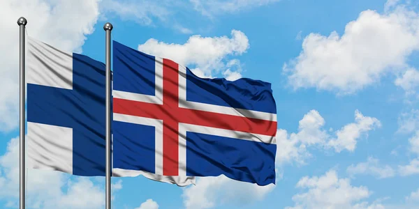 Bandera de Finlandia e Islandia ondeando en el viento contra el cielo azul nublado blanco juntos. Concepto diplomático, relaciones internacionales . — Foto de Stock