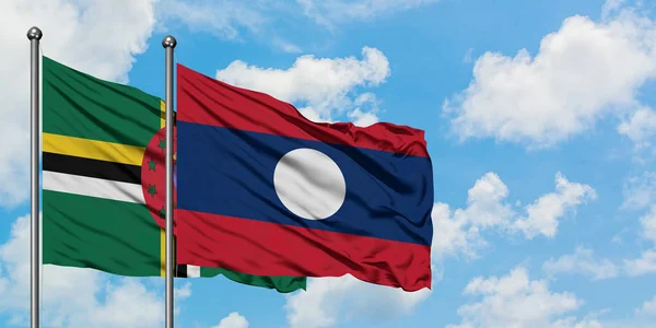 Dominica och Laos flagga viftande i vinden mot vit grumlig blå himmel tillsammans. Diplomatisk koncept, internationella relationer. — Stockfoto