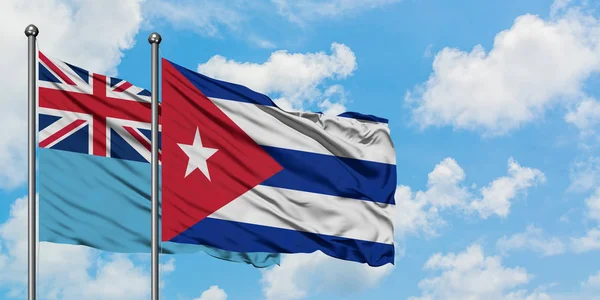 Fidschis und Kubas Flagge wehen gemeinsam im Wind gegen den wolkenverhangenen blauen Himmel. Diplomatie-Konzept, internationale Beziehungen. — Stockfoto