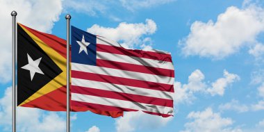 Doğu Timor ve Liberya bayrağı birlikte beyaz bulutlu mavi gökyüzüne karşı rüzgarda sallayarak. Diplomasi kavramı, uluslararası ilişkiler.