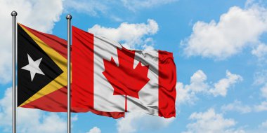 Doğu Timor ve Kanada bayrağı birlikte beyaz bulutlu mavi gökyüzüne karşı rüzgarda sallayarak. Diplomasi kavramı, uluslararası ilişkiler.