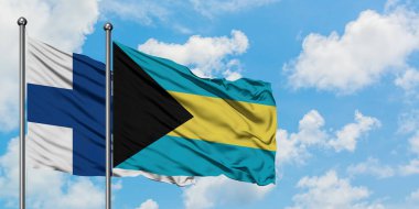 Finlandiya ve Bahamalar bayrağı birlikte beyaz bulutlu mavi gökyüzüne karşı rüzgarda sallayarak. Diplomasi kavramı, uluslararası ilişkiler.