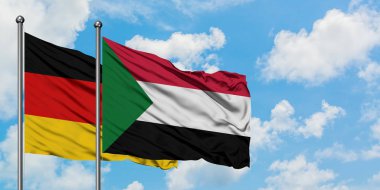 Almanya ve Sudan bayrağı birlikte beyaz bulutlu mavi gökyüzüne karşı rüzgarsal sallayarak. Diplomasi kavramı, uluslararası ilişkiler.