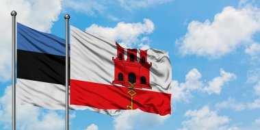 Estonya ve Cebelitarık bayrağı birlikte beyaz bulutlu mavi gökyüzüne karşı rüzgarda sallayarak. Diplomasi kavramı, uluslararası ilişkiler.