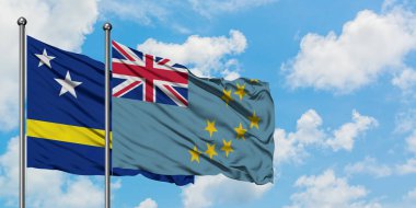 Curacao ve Tuvalu bayrağı birlikte beyaz bulutlu mavi gökyüzüne karşı rüzgarda sallayarak. Diplomasi kavramı, uluslararası ilişkiler.