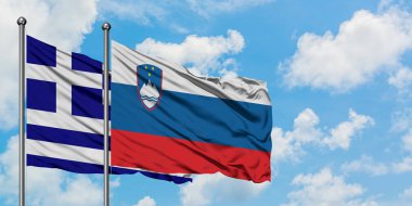 Yunanistan ve Slovenya bayrağı birlikte beyaz bulutlu mavi gökyüzüne karşı rüzgarda sallayarak. Diplomasi kavramı, uluslararası ilişkiler.