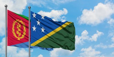 Eritre ve Solomon Adaları bayrağı birlikte beyaz bulutlu mavi gökyüzüne karşı rüzgarda sallayarak. Diplomasi kavramı, uluslararası ilişkiler.