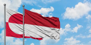 Grönland ve Monako bayrağı birlikte beyaz bulutlu mavi gökyüzüne karşı rüzgarda sallayarak. Diplomasi kavramı, uluslararası ilişkiler.