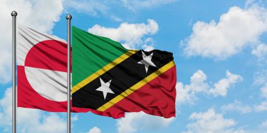 Grönland ve Saint Kitts ve Nevis bayrağı birlikte beyaz bulutlu mavi gökyüzüne karşı rüzgarda sallayarak. Diplomasi kavramı, uluslararası ilişkiler.