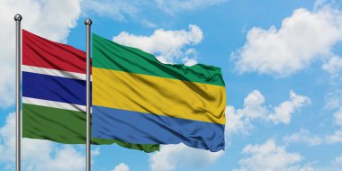 Gambiya ve Gabon bayrağı birlikte beyaz bulutlu mavi gökyüzüne karşı rüzgarda sallayarak. Diplomasi kavramı, uluslararası ilişkiler.