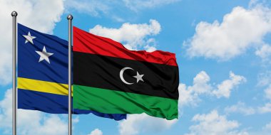Curacao ve Libya bayrağı birlikte beyaz bulutlu mavi gökyüzüne karşı rüzgarda sallayarak. Diplomasi kavramı, uluslararası ilişkiler.
