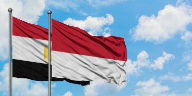 Mısır ve Monako bayrağı birlikte beyaz bulutlu mavi gökyüzüne karşı rüzgarsal sallayarak. Diplomasi kavramı, uluslararası ilişkiler.