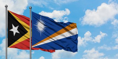 Doğu Timor ve Marshall Adaları bayrağı birlikte beyaz bulutlu mavi gökyüzüne karşı rüzgarda sallayarak. Diplomasi kavramı, uluslararası ilişkiler.