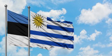 Estonya ve Uruguay bayrağı birlikte beyaz bulutlu mavi gökyüzüne karşı rüzgarda sallayarak. Diplomasi kavramı, uluslararası ilişkiler.