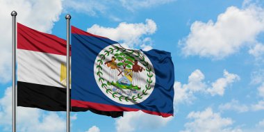 Mısır ve Belize bayrağı birlikte beyaz bulutlu mavi gökyüzüne karşı rüzgarda sallayarak. Diplomasi kavramı, uluslararası ilişkiler.