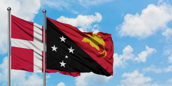 Dánsko a Papua-Nová Guinea mávajících větrem proti bíle zatažené modré obloze. Diplomacie, mezinárodní vztahy. — Stock fotografie