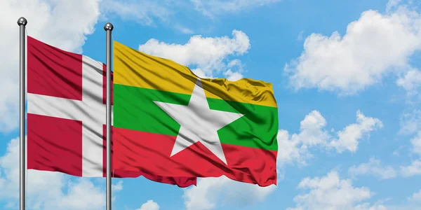 Bandera de Dinamarca y Myanmar ondeando en el viento contra el cielo azul nublado blanco juntos. Concepto diplomático, relaciones internacionales . — Foto de Stock
