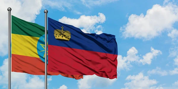 Bandera de Etiopía y Liechtenstein ondeando en el viento contra el cielo azul nublado blanco juntos. Concepto diplomático, relaciones internacionales . — Foto de Stock