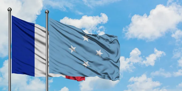 Bandera de Francia y Micronesia ondeando en el viento contra el cielo azul nublado blanco juntos. Concepto diplomático, relaciones internacionales . — Foto de Stock