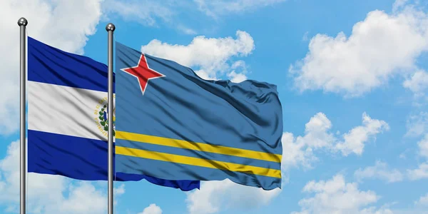 Bandera de El Salvador y Aruba ondeando en el viento contra el cielo azul nublado blanco juntos. Concepto diplomático, relaciones internacionales . — Foto de Stock