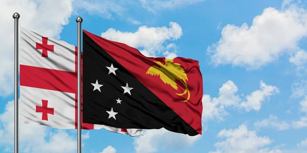 Georgia e Papua Nuova Guinea sventolano insieme la bandiera contro il bianco cielo blu nuvoloso. Concetto di diplomazia, relazioni internazionali . — Foto Stock