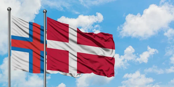 Bandera de las Islas Feroe y Dinamarca ondeando en el viento contra el cielo azul nublado blanco juntos. Concepto diplomático, relaciones internacionales . —  Fotos de Stock