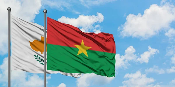 Bandera de Chipre y Burkina Faso ondeando en el viento contra el cielo azul nublado blanco juntos. Concepto diplomático, relaciones internacionales . — Foto de Stock