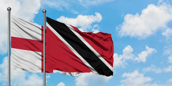 Inglaterra e Trinidad e Tobago acenando com o vento contra o céu azul nublado branco juntos. Conceito de diplomacia, relações internacionais . — Fotografia de Stock