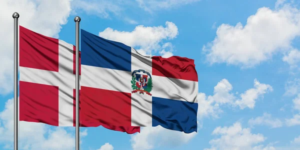 Danimarka ve Dominik Cumhuriyeti bayrağı birlikte beyaz bulutlu mavi gökyüzüne karşı rüzgarda sallayarak. Diplomasi kavramı, uluslararası ilişkiler. — Stok fotoğraf
