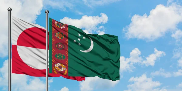 Bandera de Groenlandia y Turkmenistán ondeando en el viento contra el cielo azul nublado blanco juntos. Concepto diplomático, relaciones internacionales . — Foto de Stock