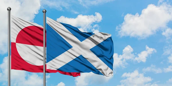 Bandera de Groenlandia y Escocia ondeando en el viento contra el cielo azul nublado blanco juntos. Concepto diplomático, relaciones internacionales . —  Fotos de Stock