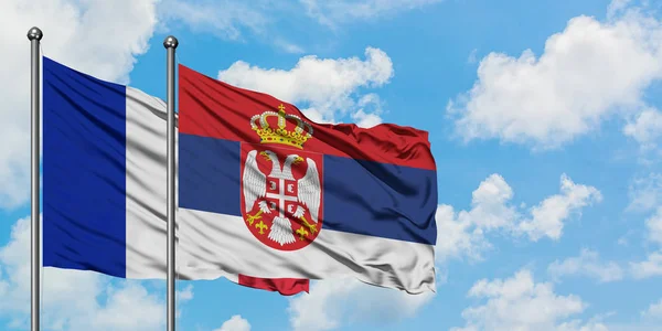 Bandera de Francia y Serbia ondeando en el viento contra el cielo azul nublado blanco juntos. Concepto diplomático, relaciones internacionales . — Foto de Stock