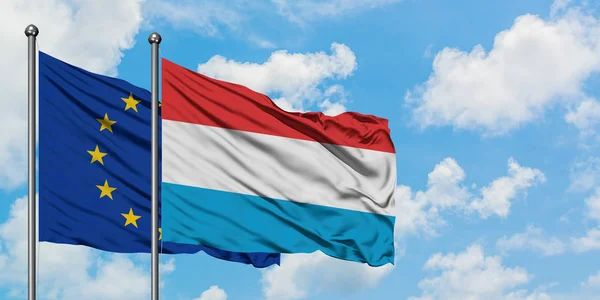 Bandera de la Unión Europea y Luxemburgo ondeando en el viento contra el cielo azul nublado blanco juntos. Concepto diplomático, relaciones internacionales . — Foto de Stock