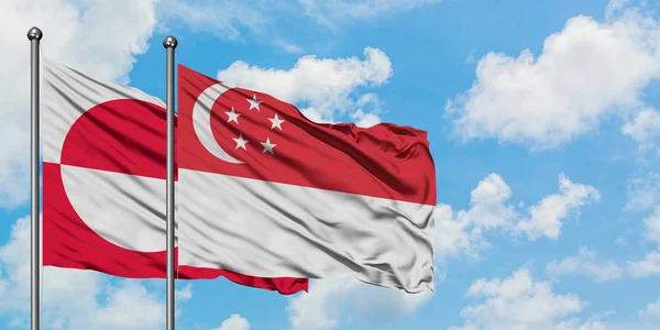 Groenlândia e Singapura acenando com o vento contra o céu azul nublado branco juntos. Conceito de diplomacia, relações internacionais . — Fotografia de Stock