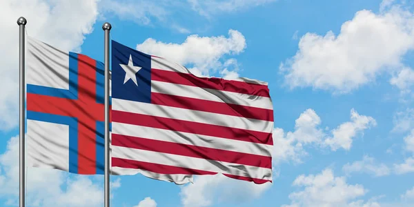 Wyspy Owcze i Liberia Flaga Macha w wiatr przed białym zachmurzone błękitne niebo razem. Koncepcja dyplomacji, stosunki międzynarodowe. — Zdjęcie stockowe