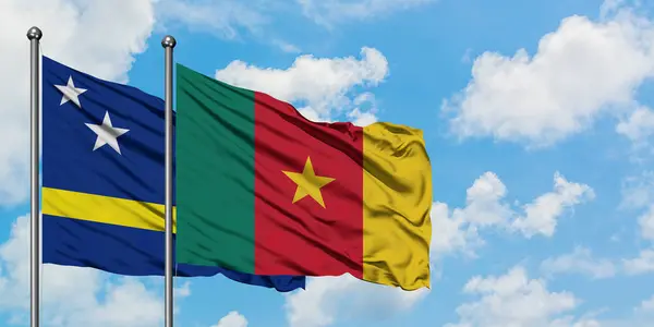 Bandera de Curazao y Camerún ondeando en el viento contra el cielo azul nublado blanco juntos. Concepto diplomático, relaciones internacionales . — Foto de Stock