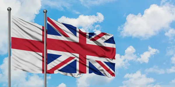 England och Storbritannien sjunker vifta i vinden mot vit grumlig blå himmel tillsammans. Diplomatisk koncept, internationella relationer. — Stockfoto