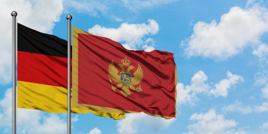 Almanya ve Karadağ bayrağı birlikte beyaz bulutlu mavi gökyüzüne karşı rüzgarsal sallayarak. Diplomasi kavramı, uluslararası ilişkiler.