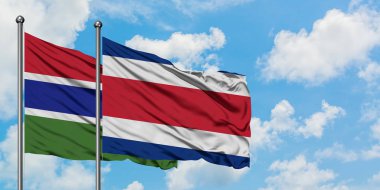 Gambiya ve Kosta Rika bayrağı birlikte beyaz bulutlu mavi gökyüzüne karşı rüzgarda sallayarak. Diplomasi kavramı, uluslararası ilişkiler.