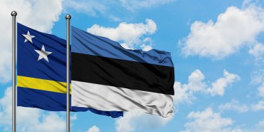 Curacao ve Estonya bayrağı birlikte beyaz bulutlu mavi gökyüzüne karşı rüzgarda sallayarak. Diplomasi kavramı, uluslararası ilişkiler.