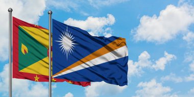 Grenada ve Marshall Adaları bayrağı birlikte beyaz bulutlu mavi gökyüzüne karşı rüzgarda sallayarak. Diplomasi kavramı, uluslararası ilişkiler.