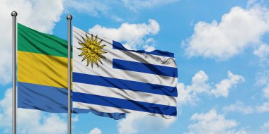 Gabon ve Uruguay bayrağı birlikte beyaz bulutlu mavi gökyüzüne karşı rüzgarda sallayarak. Diplomasi kavramı, uluslararası ilişkiler.