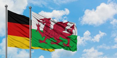Almanya ve Galler bayrağı birlikte beyaz bulutlu mavi gökyüzüne karşı rüzgarda sallayarak. Diplomasi kavramı, uluslararası ilişkiler.