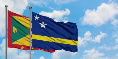 Grenada ve Curacao bayrağı birlikte beyaz bulutlu mavi gökyüzüne karşı rüzgarda sallayarak. Diplomasi kavramı, uluslararası ilişkiler.