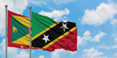Grenada ve Saint Kitts ve Nevis bayrağı birlikte beyaz bulutlu mavi gökyüzüne karşı rüzgarda sallayarak. Diplomasi kavramı, uluslararası ilişkiler.