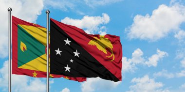 Grenada ve Papua Yeni Gine bayrağı birlikte beyaz bulutlu mavi gökyüzüne karşı rüzgarda sallayarak. Diplomasi kavramı, uluslararası ilişkiler.