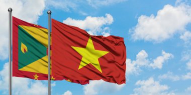 Grenada ve Vietnam bayrağı birlikte beyaz bulutlu mavi gökyüzüne karşı rüzgarda sallayarak. Diplomasi kavramı, uluslararası ilişkiler.