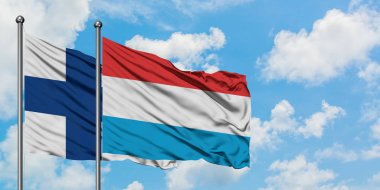 Finlandiya ve Lüksemburg bayrağı birlikte beyaz bulutlu mavi gökyüzüne karşı rüzgarsal sallayarak. Diplomasi kavramı, uluslararası ilişkiler.